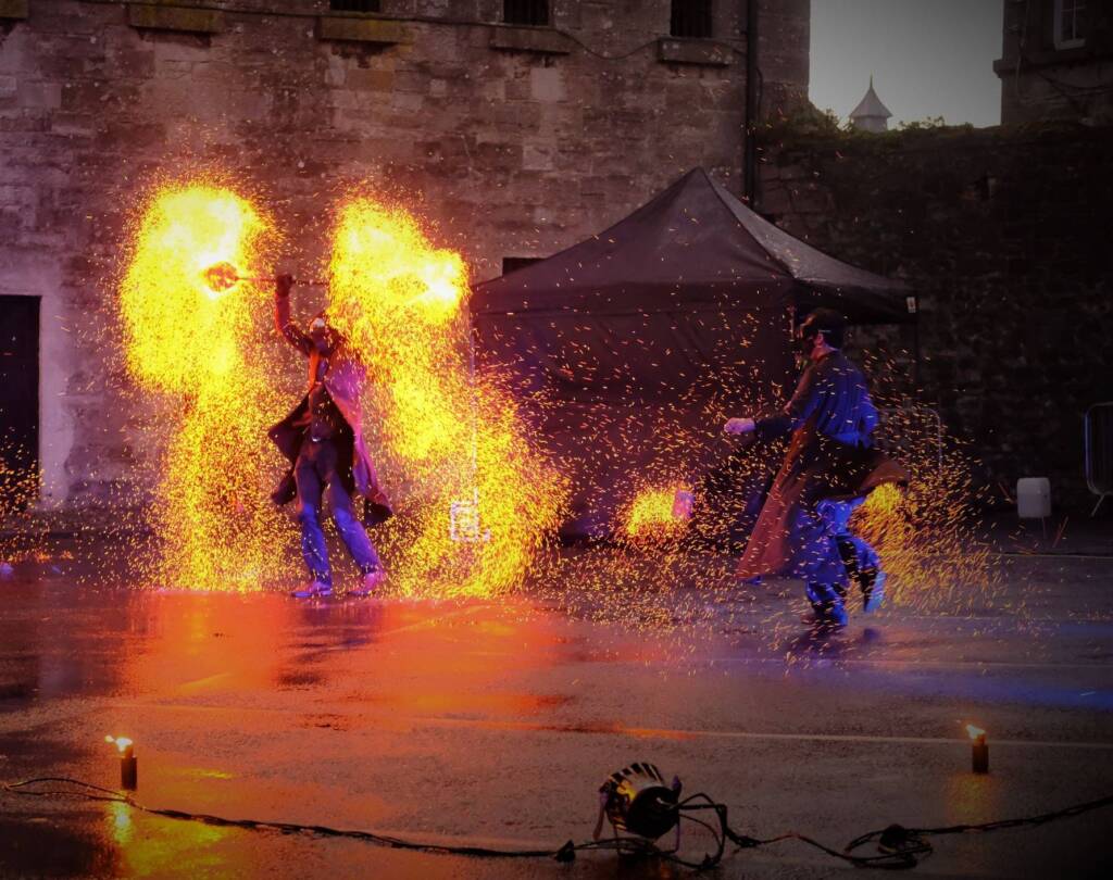 Fire dancers are caught mid show showering themselves in bright sparks