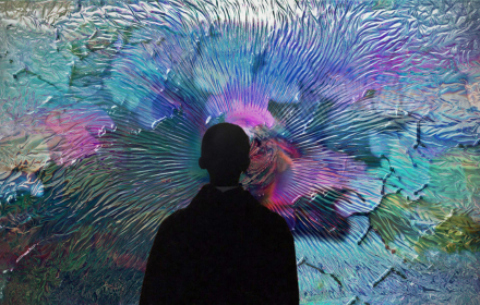 A silhouetted person stands in front of a screen of multicoloured, flowing abstract forms