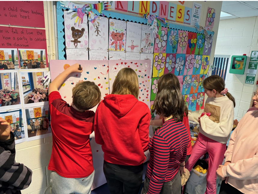 A group of students working on a wall filled with colourful artwork.