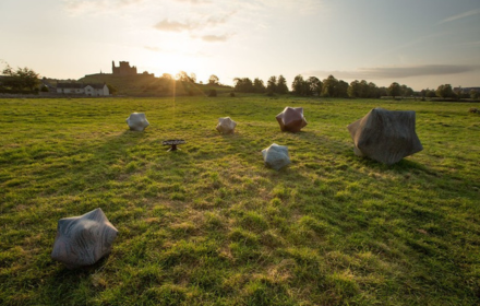 Rocks carved in the shape of stars in various sizes sit in a sunny field